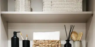 Bathroom cabinet with toilet paper rolls, white bath towels and cosmetics bottles