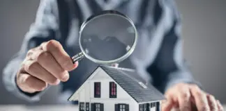 House with man holding magnifying glass concept for home inspection or searching for a new house