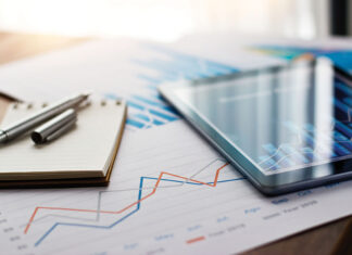 Business document report on paper and tablet with sales data and financial business growth graph on table background.