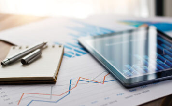 Business document report on paper and tablet with sales data and financial business growth graph on table background.