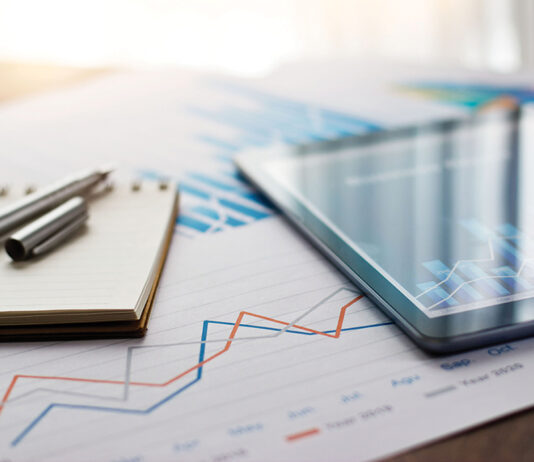 Business document report on paper and tablet with sales data and financial business growth graph on table background.