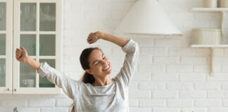 Happy millennial woman have fun cooking breakfast in kitchen