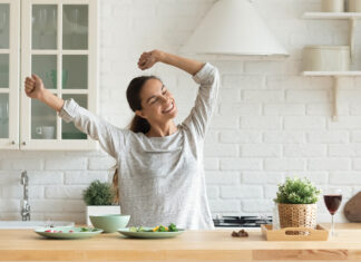 Happy millennial woman have fun cooking breakfast in kitchen