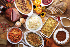 Thanksgiving table with roasted turkey, sliced ham and side dishes