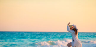 Young happy woman in swimsuit on white beach