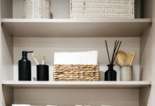 Bathroom cabinet with toilet paper rolls, white bath towels and cosmetics bottles