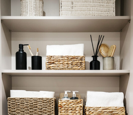 Bathroom cabinet with toilet paper rolls, white bath towels and cosmetics bottles