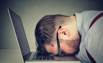 Stressed man lying on laptop