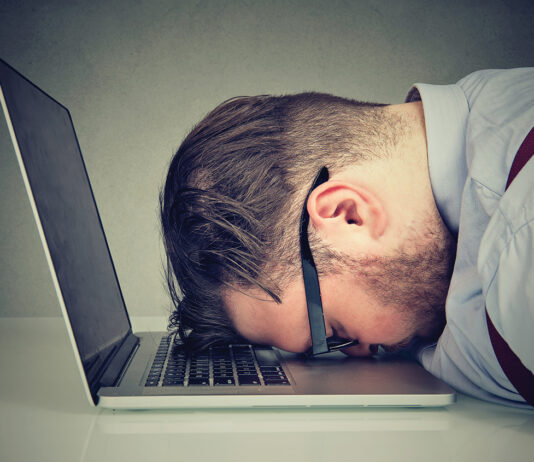 Stressed man lying on laptop
