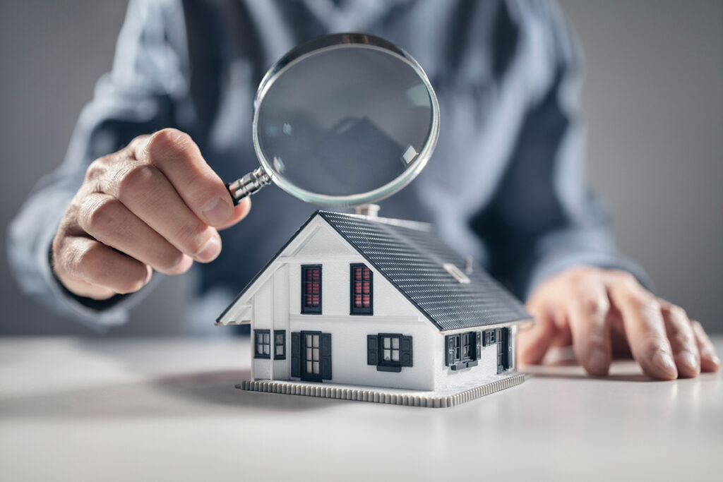 House with man holding magnifying glass concept for home inspection or searching for a new house