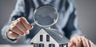 House with man holding magnifying glass concept for home inspection or searching for a new house