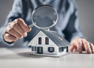 House with man holding magnifying glass concept for home inspection or searching for a new house