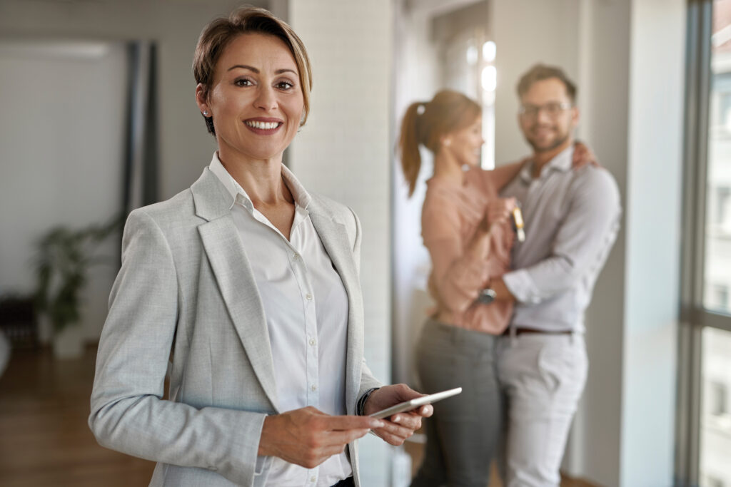 Real estate agent with a couple in the background.