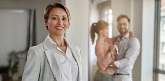 Real estate agent with a couple in the background.