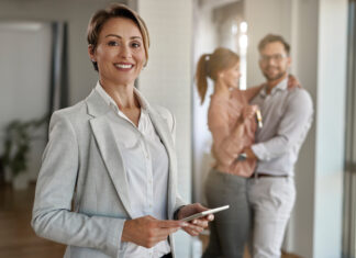 Real estate agent with a couple in the background.