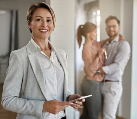 Real estate agent with a couple in the background.