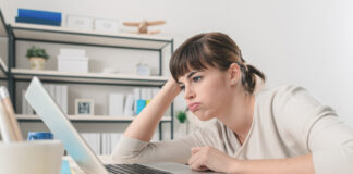 Tired disappointed woman working at office desk with a laptop, connection and computer problems concept