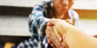 Close-up handshake for help homeless man on walking street in the capital city.