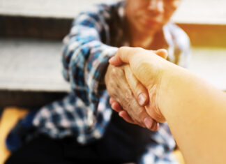 Close-up handshake for help homeless man on walking street in the capital city.