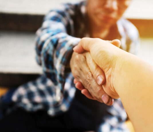 Close-up handshake for help homeless man on walking street in the capital city.