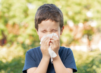 Allergic child sneezing covering nose