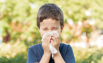 Allergic child sneezing covering nose