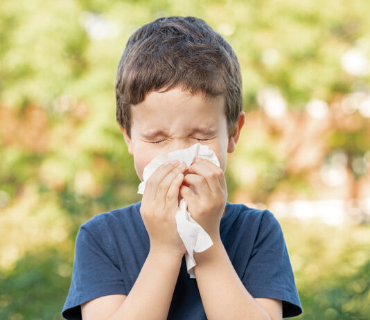 Allergic child sneezing covering nose