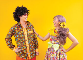 Asian hippie couple dress in 80s colorful vintage fashion with retro clothing while dancing together isolated on yellow background for fancy outfit party and pop culture