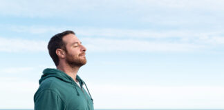 Relaxed man breathing fresh air with the sea at the background.